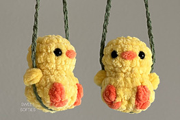 tiny crochet amigurumi birds sitting on a yarn swing