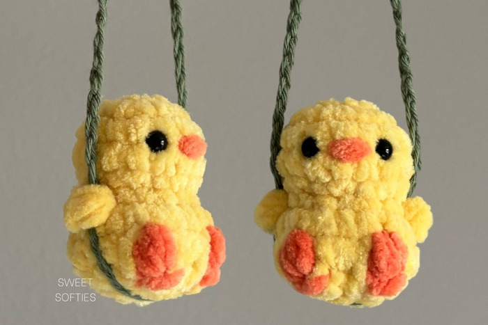 tiny crochet amigurumi birds sitting on a yarn swing