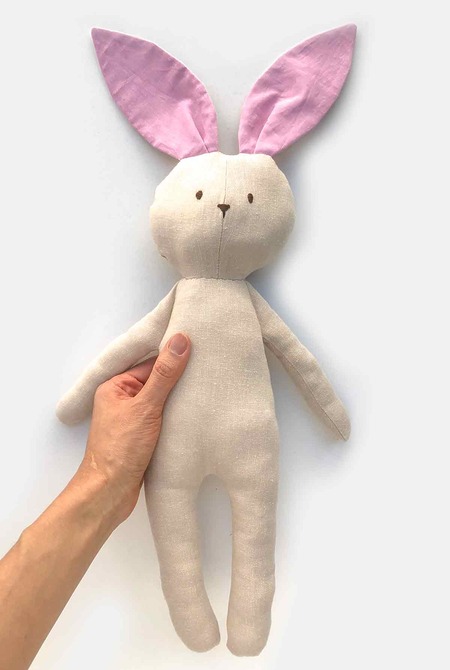 A long, skinny handmade fabric bunny doll that can wear a removable outfit