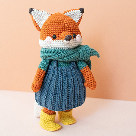 Rita Fox: A crocheted amigurumi fox standing upright, wearing a miniature blue dress, a cozy scarf, and tiny boots